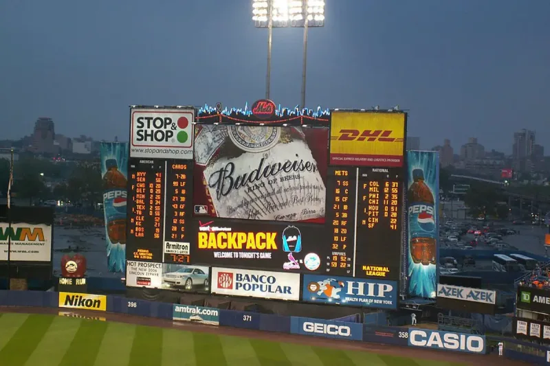 Wide stadium LED screen displaying live sports video and score information