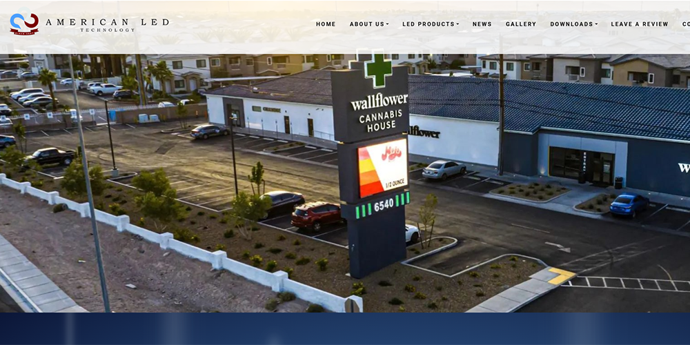 Aerial view of a shopping plaza with a tall Wallflower Cannabis House sign and surrounding parking lots
