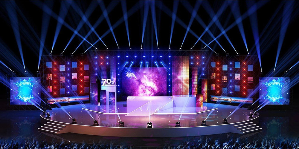 租1 - LED Screen Board - LED Screen Board Large illuminated concert stage with blue and white spotlights, LED panels, and several platforms for a live show at night.