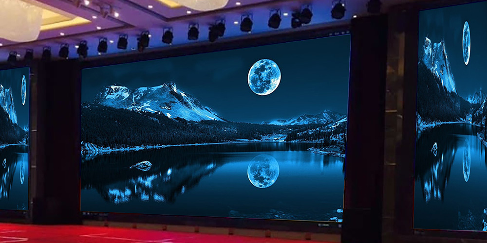 租3y - LED Screen Board - LED Screen Board Blue-toned conference hall displays with large screens showing a snowy mountain lake at night and a full moon, reflecting on the water.
