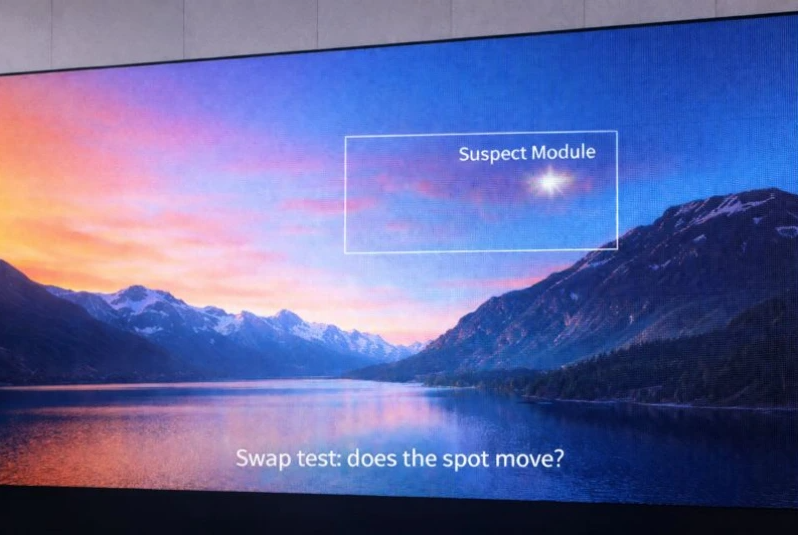 Photo of a presentation slide on a monitor: a landscape image with a highlighted box labeled 'Suspect Module' and the caption 'Swap test: does the spot move?'