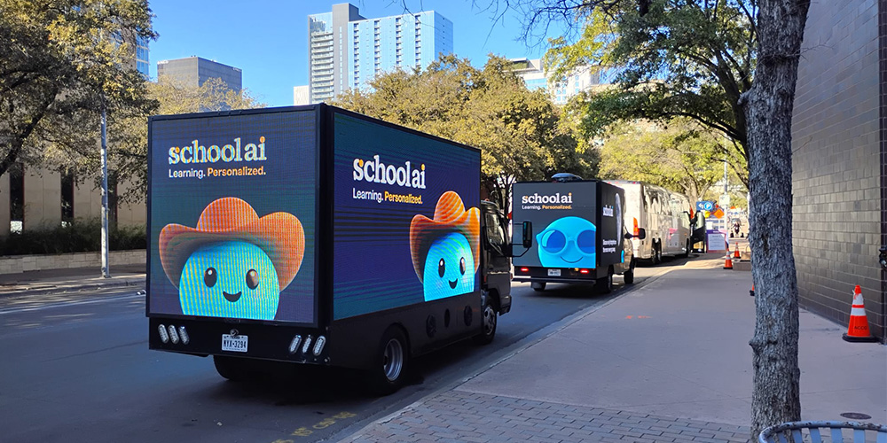 02-mobile-billboard-truck-campaign-fleet - LED Screen Board - LED Screen Board Schoolai delivery trucks with a blue mascot and the slogan 'Learning. Personalized.' parked on a city street.