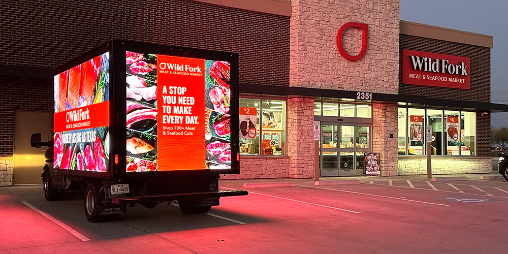 03-led-billboard-truck-retail-location - LED Screen Board - LED Screen Board Delivery truck with a large digital billboard displaying meat ads in front of Wild Fork Meat & Seafood Market.