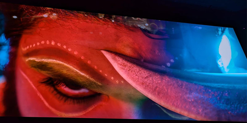 08-Swagath-Onyx-Theatre - LED Screen Board - LED Screen Board Close-up of an eye under red and blue neon light, with white dotted makeup lines across the brow.