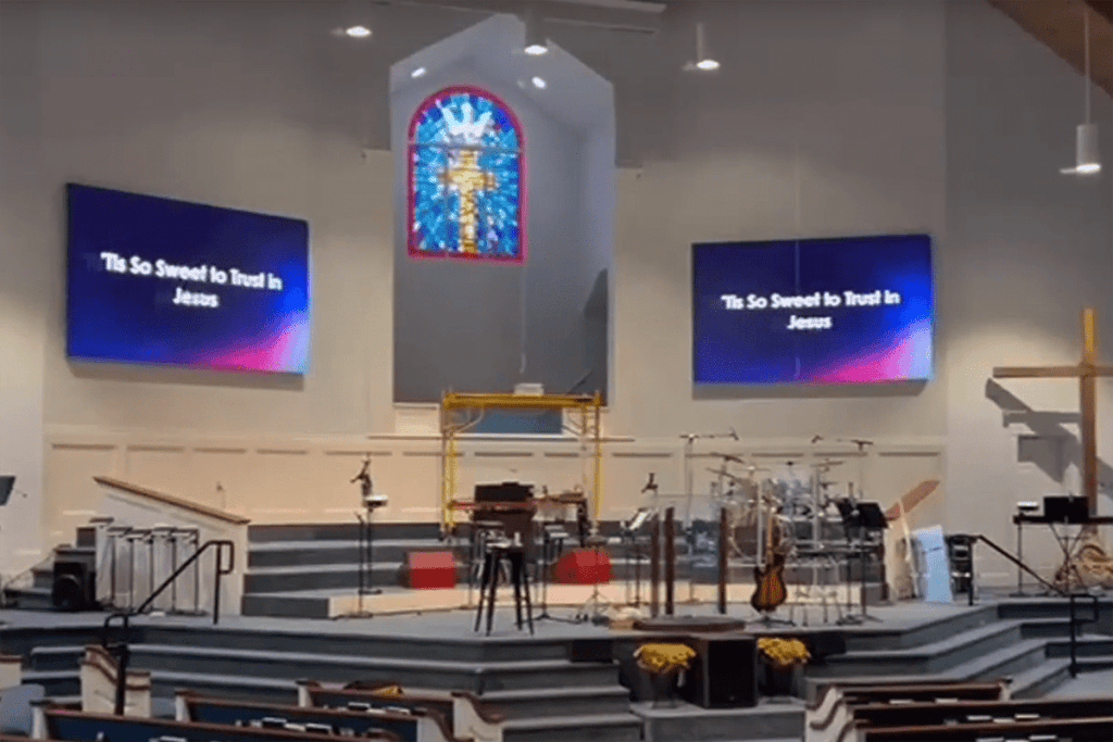 Two LED video walls displaying worship lyrics in a church sanctuary